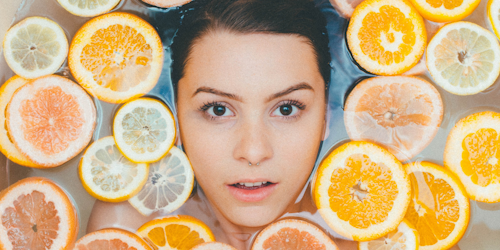 Woman's face in bathwater surrounded by orange slices