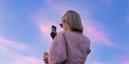 Female blonde with phone watching sunset