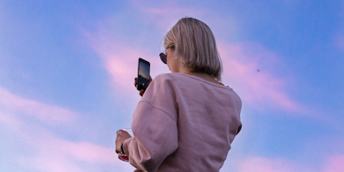 Female blonde with phone watching sunset