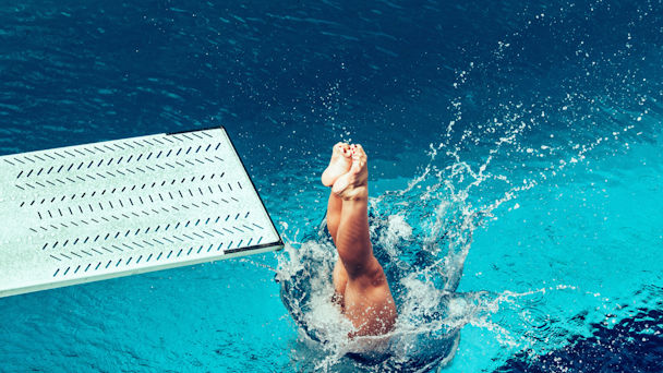 Woman diving off diving board into swimming pool
