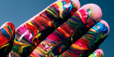 Hand covered in various colored paint