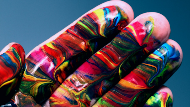 Hand covered in various colored paint