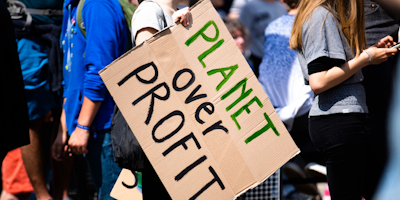 Woman holding protest sign that reads: "Planet Over Profit"