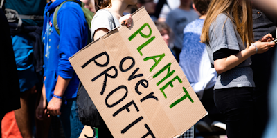 Woman holding protest sign that reads: "Planet Over Profit"