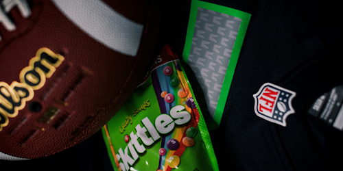 NFL logo, Wilson football and pack of sour Skittles together