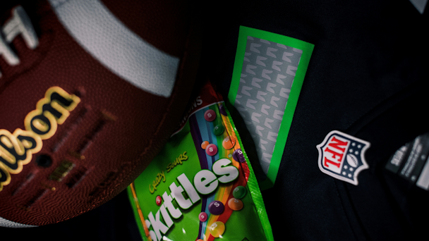 NFL logo, Wilson football and pack of sour Skittles together