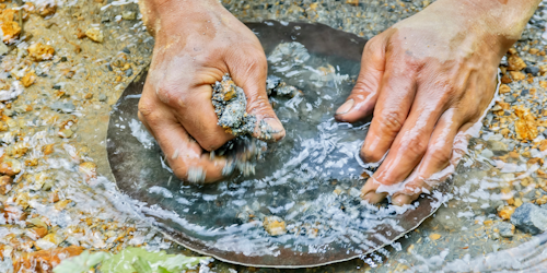 Hands panning for gold in a river