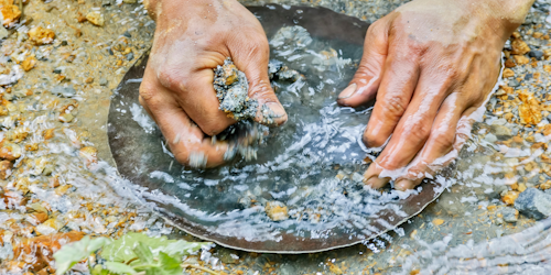 Hands panning for gold in a river