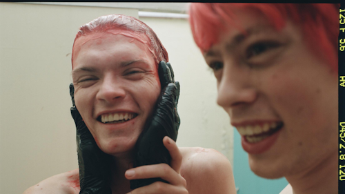 Two people dyeing their hair bright red