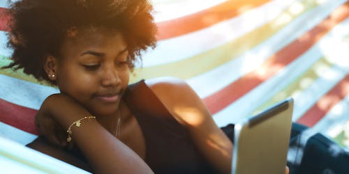 Black woman laying in hammock reading from a tablet Black woman laying in hammock reading from a tablet
