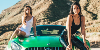 Influencers leaning against green Mercedes in the desert