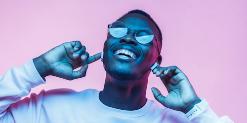 Man wearing glasses and earbuds against pink background