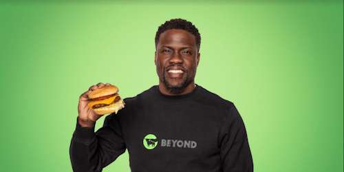 Kevin Hart holding a Beyond Meat burger against a green backdrop