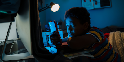 Kid using computer and phone in dark room