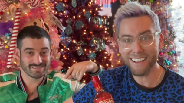 Lance Bass and his husband Michael Turchin in front of three Christmas trees