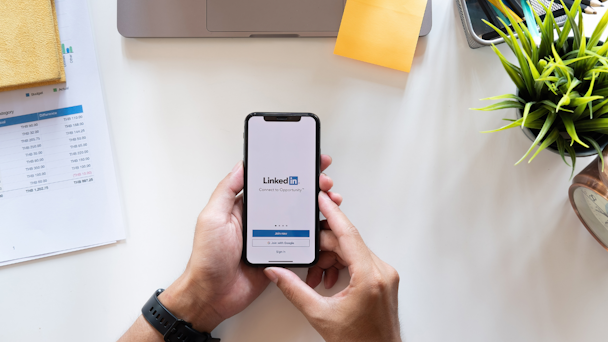 Man holding phone with LinkedIn logo on mobile screen