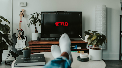 Netflix on TV screen with man's feet in foreground