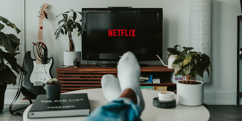 Netflix on TV screen with man's feet in foreground