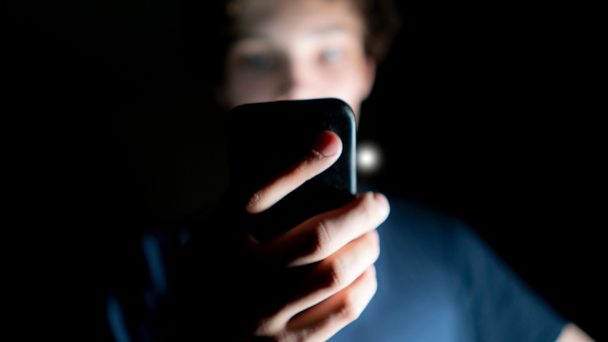 Guy holding cell phone in dark room