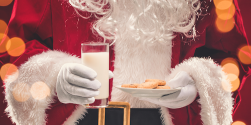 Santa holding a glass of milk and cookies