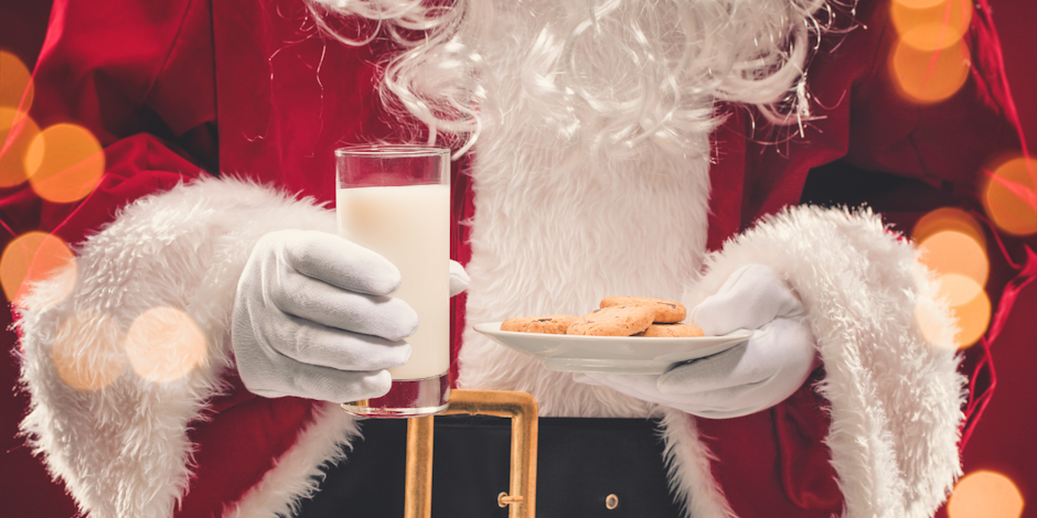 Santa holding a glass of milk and cookies