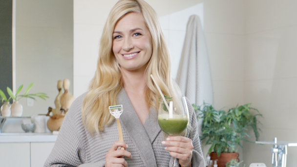 Beth Behrs holding razor and green juice in wine glass
