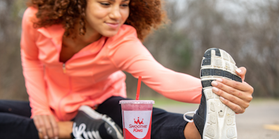 Woman stretching with Smoothie King smoothie in forefront