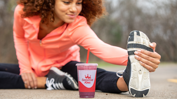 Woman stretching with Smoothie King smoothie in forefront