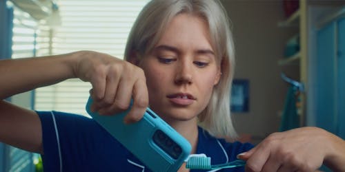 Woman using toothpaste from her phone Woman using toothpaste from her phone