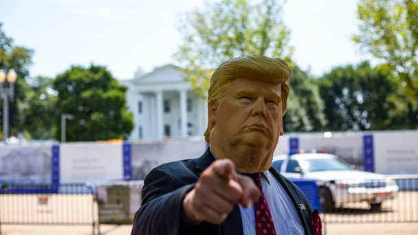 Man wearing Donald Trump rubber Halloween-style mask