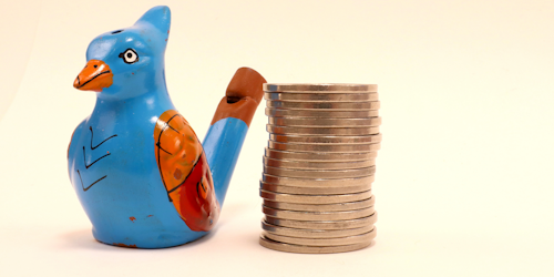 Wooden bird next to stack of coins