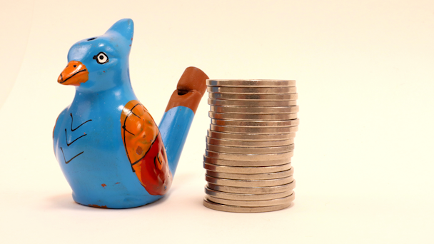 Wooden bird next to stack of coins