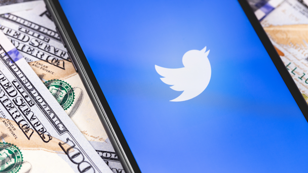 Twitter logo on phone on top of pile of cash
