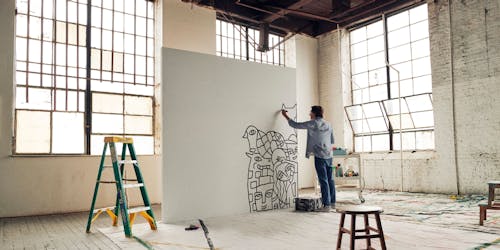 Uniball campaign image of man making art in large open studio space Uniball campaign image of man making art in large open studio space