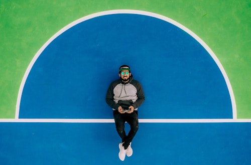A man with a videogame controller lying down on a sports court