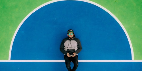 A man with a videogame controller lying down on a sports court