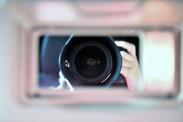 A camera lens looking through a window, reflected in a mirror