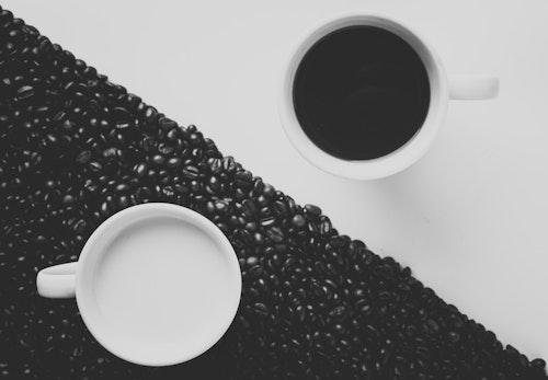 A cup of coffee and a cup of milk, each on the opposite-colored background, as in a yin-and-yang symbol