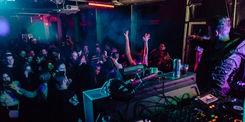 A DJ playing to a packed basement room