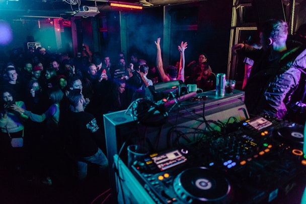 A DJ playing to a packed basement room