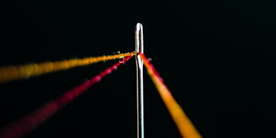 Lines of thread in the eye of a needle