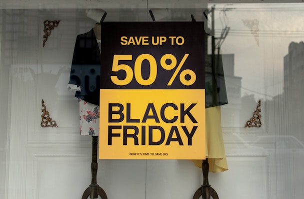 A sign that reads "save up to 50% Black Friday" in a shop window