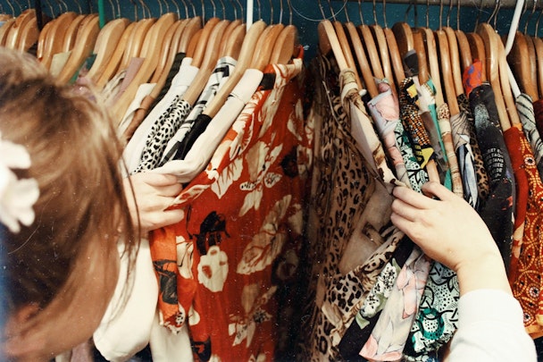 A shopper parting a rail of clothing, like a curtain