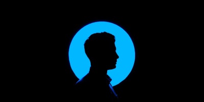 A man in silhouette against a background featuring a blue lighted circle