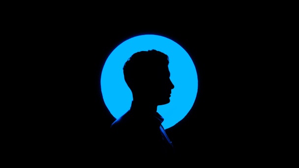 A man in silhouette against a background featuring a blue lighted circle