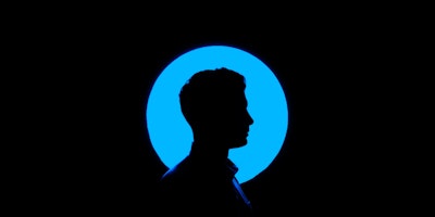 A person's head, in silhouette and profile, against a blue circular light