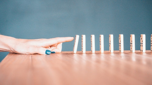 A finger, knocking over a row of dominos
