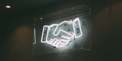 A neon sign depicting a handshake
