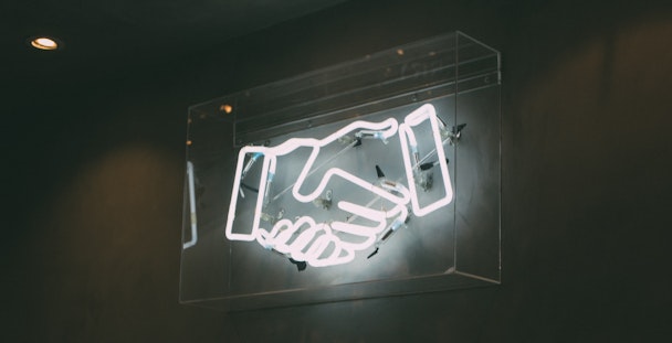 A neon sign depicting a handshake
