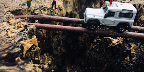 Lego figures acting out a dangerous tree-trunk-bridge crossing by a jeep